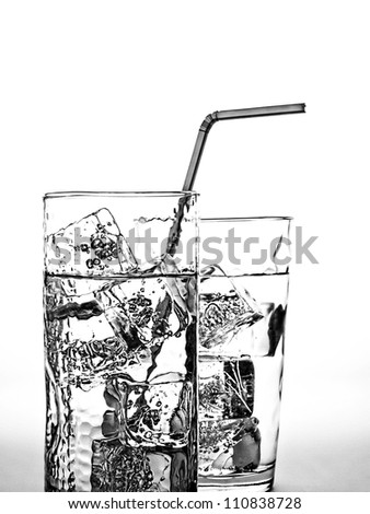 Black and white photo of glass of water with ice cubes and straw.