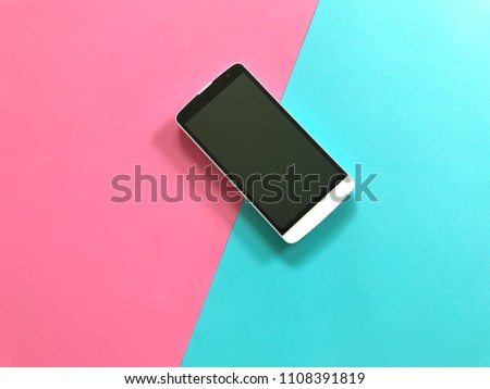 A white smartphone on pastel pink and blue background. Top view with copy space. Selective focus.