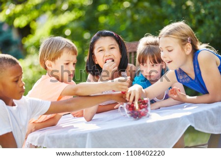 Interracial group of children eating cherries in garden in summer