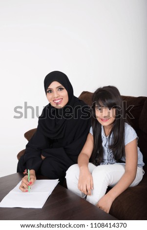 Arab woman teaching her daughter on white background