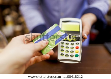 Picture of buyer with bank card and seller with terminal in hand
