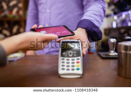 Photo of seller man with terminal and buyer with smartphone