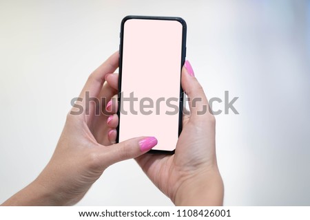 Pink nail polish hand holding or using mobile phone.
