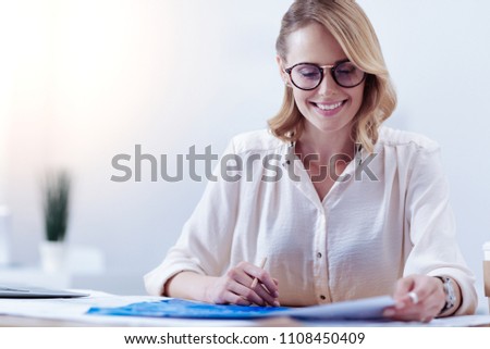 Female engineer. Pleasant positive smart woman looking at the technical blueprint and studying it while working on a project