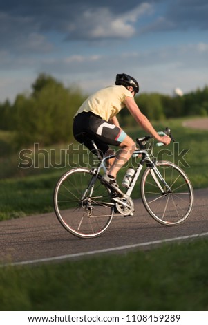 Cyclist man riding road sport bike in sunny day on a mountain road
