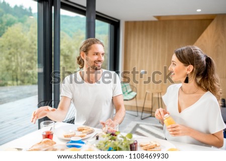 Young couple having fun during a breakfast time sitting at the kitchen of the modern house interior