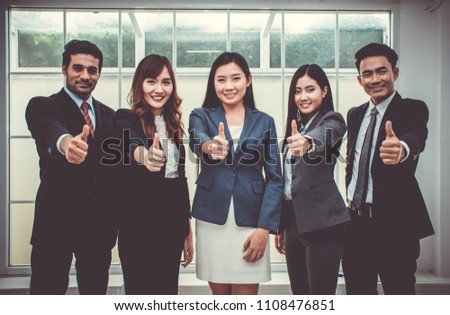 Successful business people are giving a thumb up with a big smile at the office or meeting room