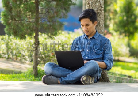 Asian young  man using computer outdoor Royalty-Free Stock Photo #1108486952