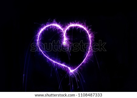 Unique purple heart, hand drawn by sparklers, using long exposure, on a dark background. 