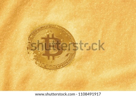 Coin crypto currency gold bitcoin, on a background of golden sand. Business Concept