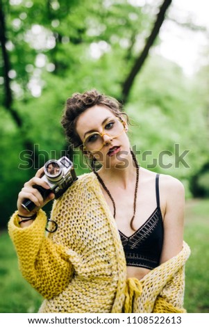 Portrait of young woman using an vintage cinema camera in a park