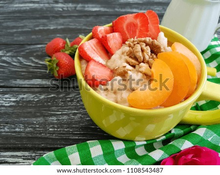 oatmeal, nuts, strawberries on a black wooden background