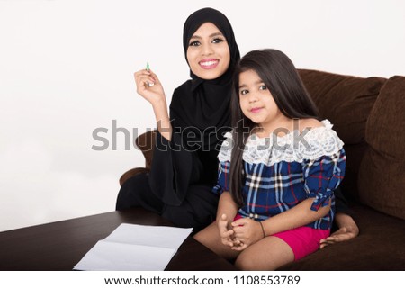 Arab woman teaching her daughter on white background