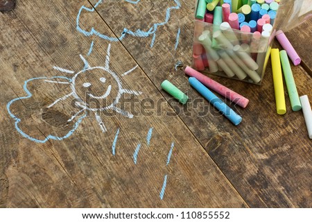 Child's drawings and colored chalk on wooden background Royalty-Free Stock Photo #110855552