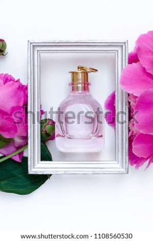 Bottle of perfume pink color in frame with peony flower Flat lay Nature concept on white background with copy space for greeting message creative layout. Summer spring background concept.