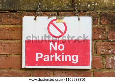 A street sign against a brick wall warns drivers that it is a no parking area