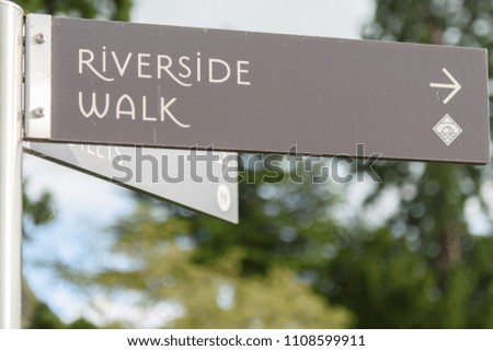A sign directs walkers and hikers along a riverside walk