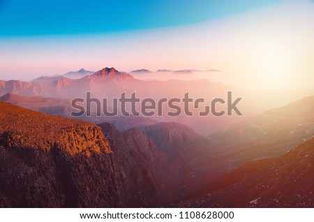 A view of the majestic Jebel Jais mountain in Ras Al Khaimah, United Arab Emirates from the highest viewing area during sunset. Royalty-Free Stock Photo #1108628000