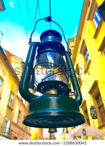 old lantern shaped street lamp green color background sky buildings.