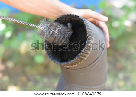 Man cleaning chimney pipe outside. Cleaning a wood burning stove. Chimney sweep cleaning