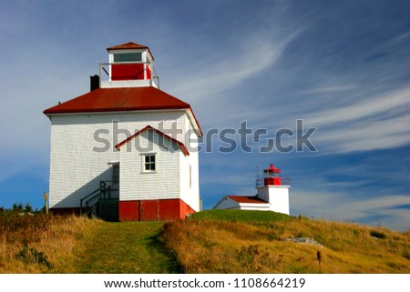 A white and red lighthouse sits as a beacon in Port Bickerton, Nova Scotia. 