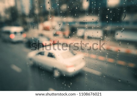 Rain drops on car window with road light bokeh. Stock image of rain drops on car glass in rainy season abstract background, water drop on the glass, night storm raining car driving concept