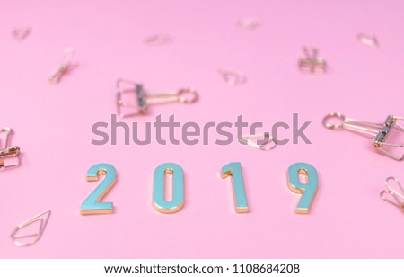 Flat lay of the word 2019 in new year concept with golden binder clips on pink pastel background.