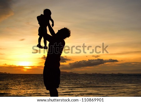 silhouette of daddy and small girl on the beach at dusk.