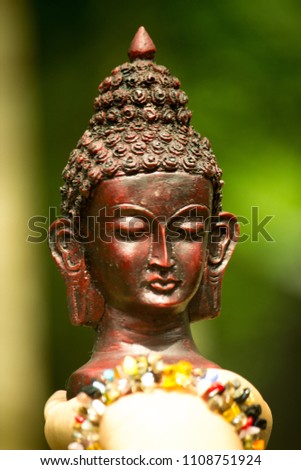 Small, black bust sculpture of Lord Buddha on hand