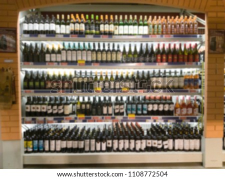 Blurred image of wine shelves display in supermarket. Defocused Rows of Wine Liquor bottles on the store shelf. Alcoholic beverage abstract background. Alcohol drink market concept. Royalty-Free Stock Photo #1108772504