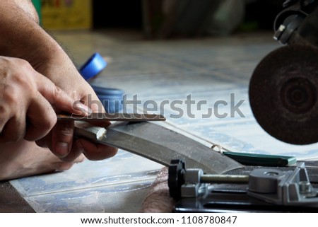          Hand of man use old metal file sharpening big knife with blurred floor background                      