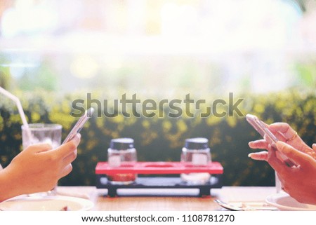 Two female using mobile phone on food table