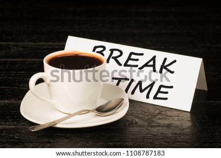 A cup of coffee on a background of plates with the words break time on black boards