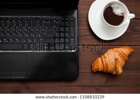 hot chocolate with a croissant near the laptop