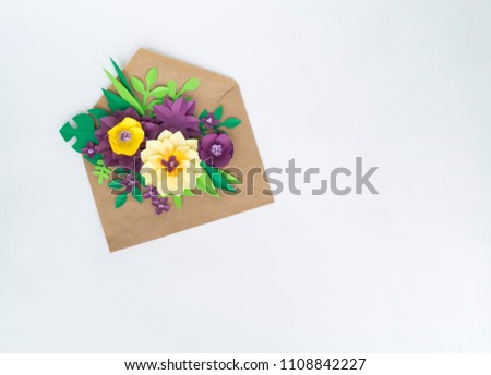 A kraft envelope and flowers made of paper. Apartment, top view. Letter and a present in eco paper on white background.Valentine's day or other holiday concept, top view. Hobbies for the child.