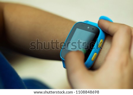 Boy using smartwatch sending a message, wearable children tracking gadget with touch screen and calling service