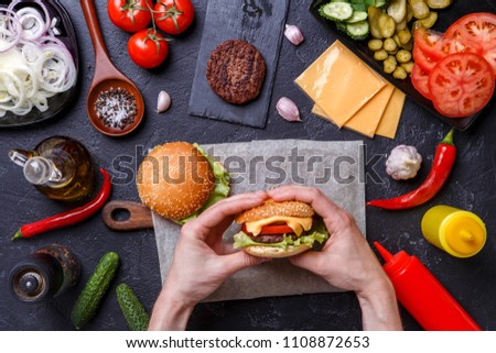 Photo on top of two hamburgers, human hands, chili peppers,
