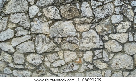 Light aged stonework with dark clay seams. Old mossy stonewall. Masonry in free style. Limestone