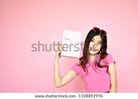 beautiful portrait Asian girl holding gift box, cute woman in casual clothes with beaming smile standing on pink background