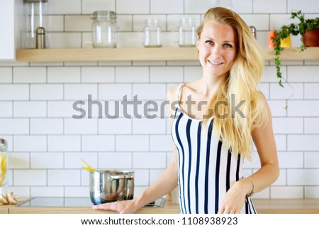 Portrait of beautiful woman in long striped dress in kitchen