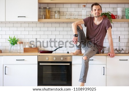 Photo of man sitting in kitchen with phone in hands