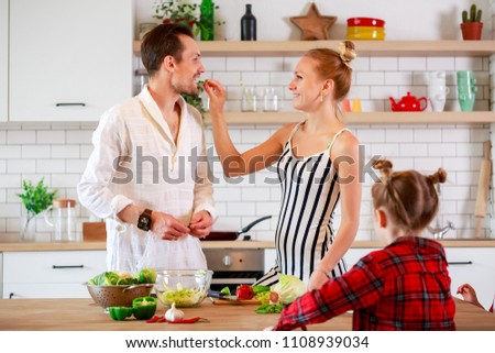 Photo of happy parents and daughters at a table with vegetables
