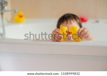 Happy little baby in the bathroom playing with rubber yellow dots. Infant training and bathing. Hygiene and care for young children.
