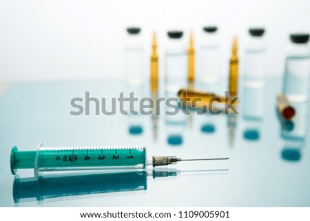 Medical Vaccine vial hypodermic injection treatment disease care in hospital and prevention illness. against a background of medical bottles with injection, drug or vitamin