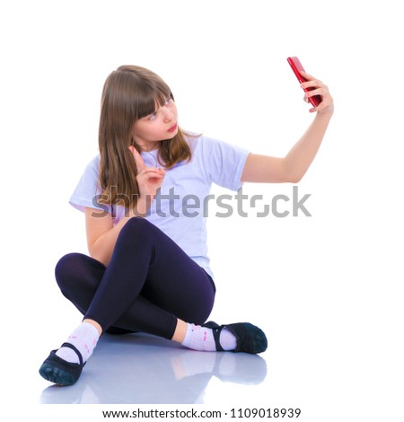 Happy smiling little girl making self-portrait on smartphone. The concept of people and technology. Isolated on white background.