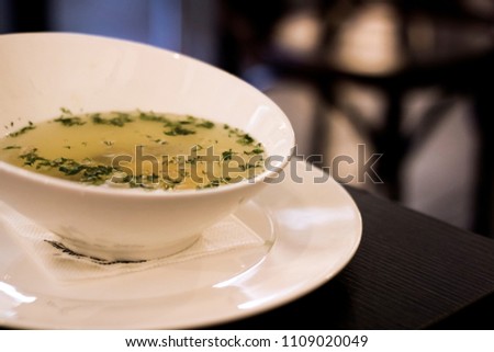 Chicken broth with herbs on a wooden table, healthy food