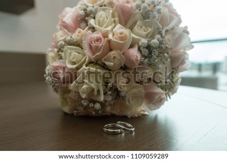 Beautiful toned picture with wedding rings lying on a wooden table a bouquet of flowers in the background
