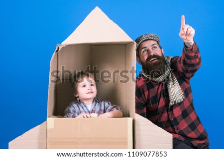 Father`s day. Happy family playing with cardboard rocket. Cosmonaut concept. Cute boy playing cosmonaut. Child's dream. Boy is sit in cardboard space rocket. Parenthood concept. Father teaches son.