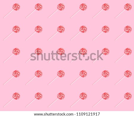 Seamless partern with striped sweet lollipops over the pink background