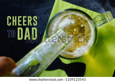 Cheers to dad father's day or birthday graphic, beer being poured into mug.  Retro style black and green colors with bow tie in background.  View from above of drink on horizontal photograph.  